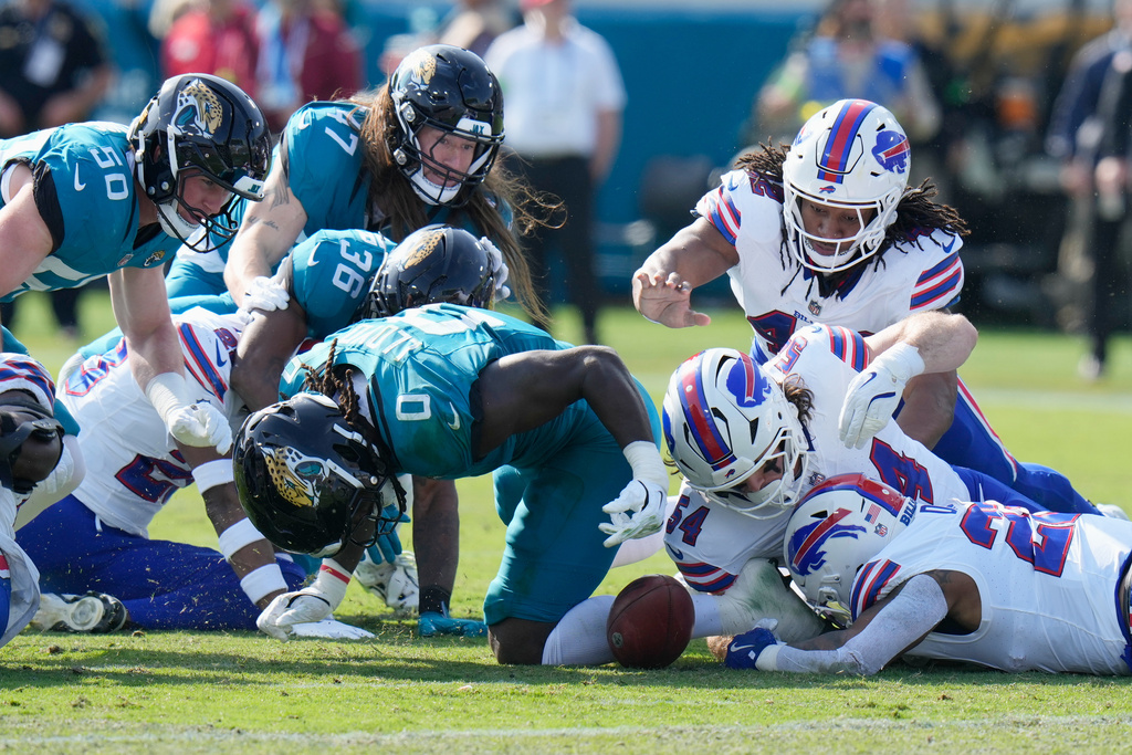 Buffalo Bills' Ray Davis, bottom right, fumbles a kickoff return from the Jacksonville Jaguars as teammate Baylon Spector (54) and Jacksonville Jaguars' Devin Lloyd (0) try to recover the ball during the first half of an NFL wild-card playoff football game Sunday, Jan. 11, 2026, in Jacksonville, Fla. (AP Photo/Chris O'Meara)
