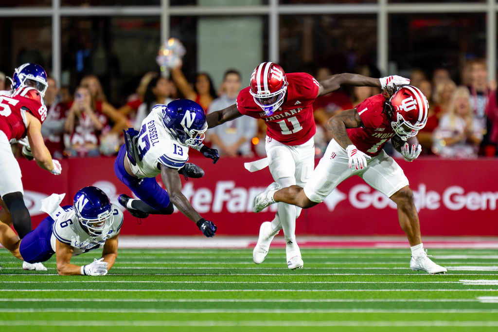 Indiana running back Turbo Richard (1) breaks away from a tackle-attempt by Northwestern defensive backs Josh Fussell (13) and Robert Fitzgerald (6) during the first half of an NCAA college football game, Friday, Sept. 25, 2026, in Bloomington, Ind. (AP Photo/Doug McSchooler)