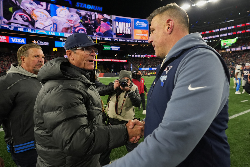 Los Angeles Chargers head coach Jim Harbaugh, left, and New England Patriots head coach Mike Vrabel, right, shake hands after their NFL wild-card playoff football game in Foxborough, Mass., Sunday, Jan. 11, 2026. (AP Photo/Charles Krupa)