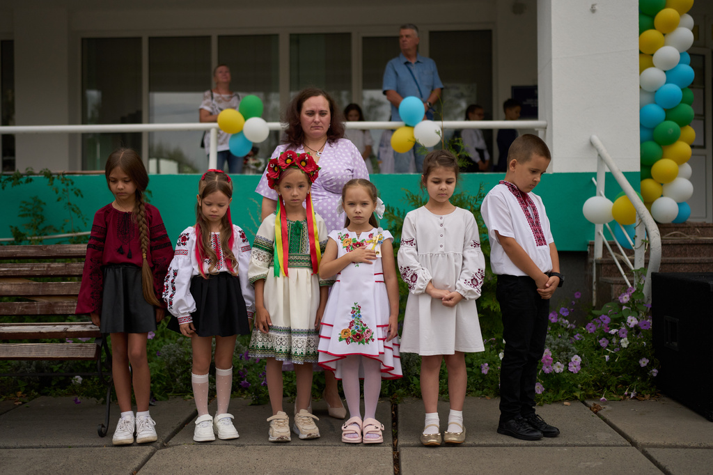 Children and teachers observe a daily nationwide minute of silence in memory of soldiers killed in the war with Russia during the traditional back to school celebrations in Kyiv, Tuesday, Sept. 1, 2026. (AP Photo/Francisco Seco)