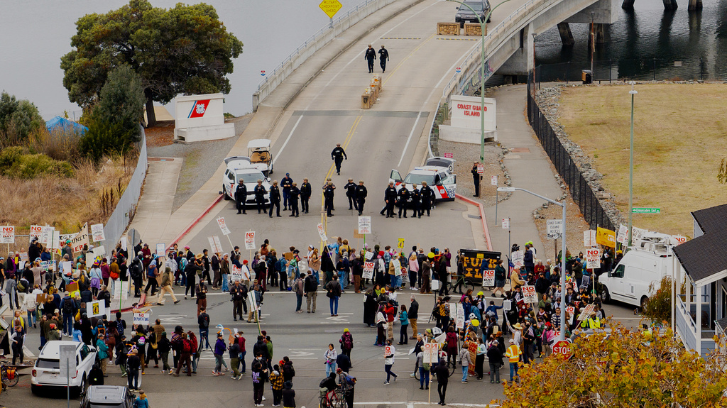 EDS NOTE: OBSCENITY - Protesters block the entrance to Coast Guard Base Alameda shortly after a caravan of U.S. Customs and Border Protection personnel arrived on Thursday, Oct. 23, 2025, in Oakland, Calif. (AP Photo/Noah Berger)