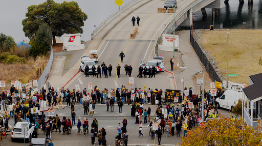 EDS NOTE: OBSCENITY - Protesters block the entrance to Coast Guard Base Alameda shortly after a caravan of U.S. Customs and Border Protection personnel arrived on Thursday, Oct. 23, 2025, in Oakland, Calif. (AP Photo/Noah Berger) EDS NOTE: OBSCENITY - Protesters block the entrance to Coast Guard Base Alameda shortly after a caravan of U.S. Customs and Border Protection personnel arrived on Thursday, Oct. 23, 2025, in Oakland, Calif. (AP Photo/Noah Berger)