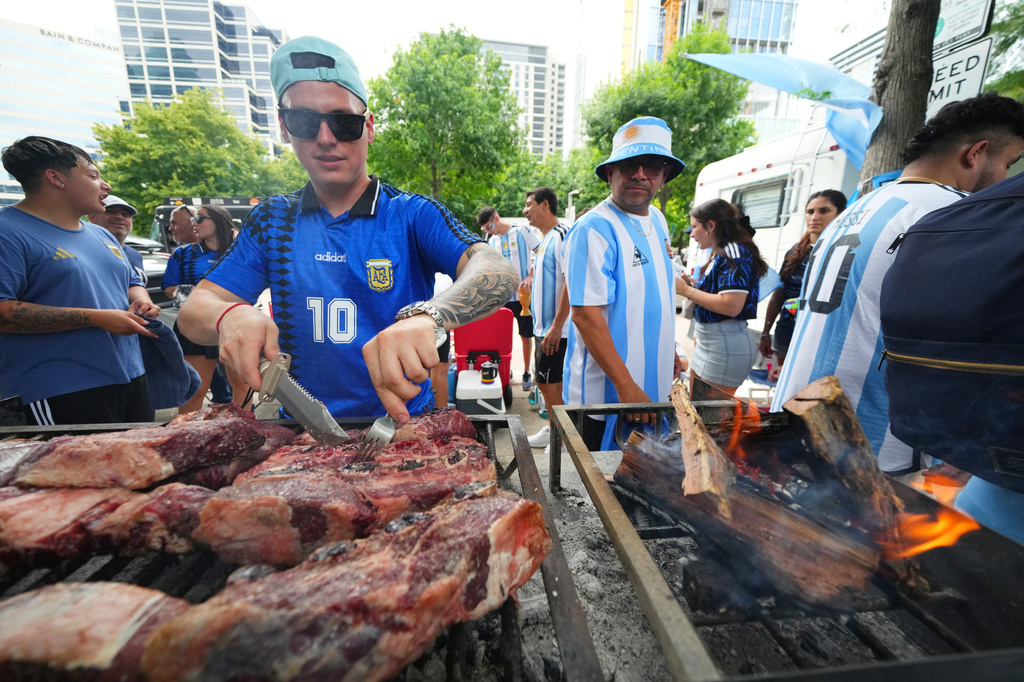 Matias Videla, of Dallas, a supporter of Argentina, checks meat on his grill during a rally ahead of his team's World Cup Group J soccer match against Austria, Sunday, June 21, 2026, in Dallas. (AP Photo/Julio Cortez)