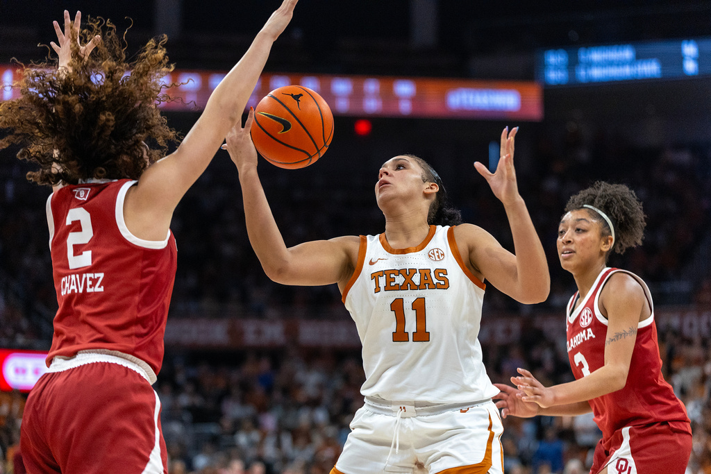 Texas forward Justice Carlton (11) reaches for a rebound between Oklahoma guards Aaliyah Chavez (2) and Zya Vann, right, during the second half of an NCAA college basketball game Sunday, Feb. 1, 2026, in Austin, Texas. (AP Photo/Stephen Spillman)
