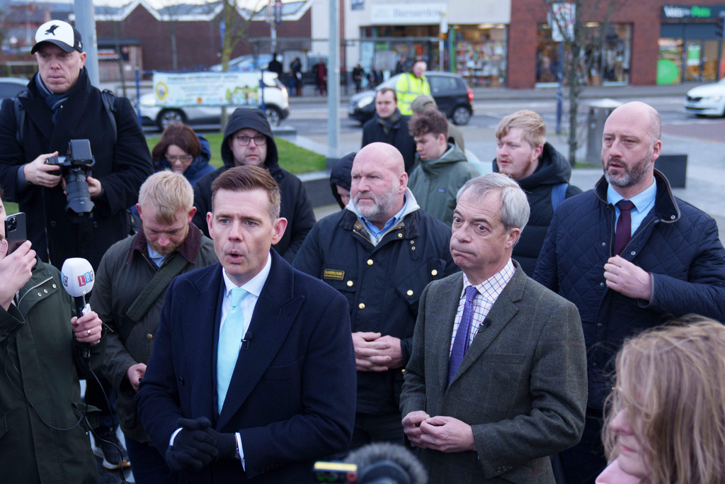 Reform leader Nigel Farage, centre right, stands with prospective candidate Matt Goodwin, centre left, and supporters during a campaign visit to Gorton and Denton in Manchester, England, Friday, Jan. 30, 2026. (AP Photo/Jon Super)