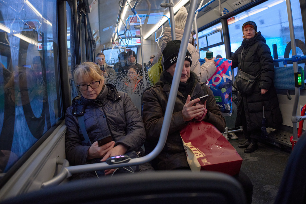 FILE - Passengers look at their smartphones on a bus in Moscow, Russia, Nov. 17, 2025. (AP Photo/Alexander Zemlianichenko, File)