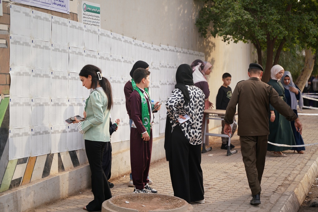Voters search for their names before entering a polling station to vote during parliamentary elections in Kirkuk, northern Iraq, Tuesday, Nov. 11, 2025. (AP Photo/Sirwan Tahir)
