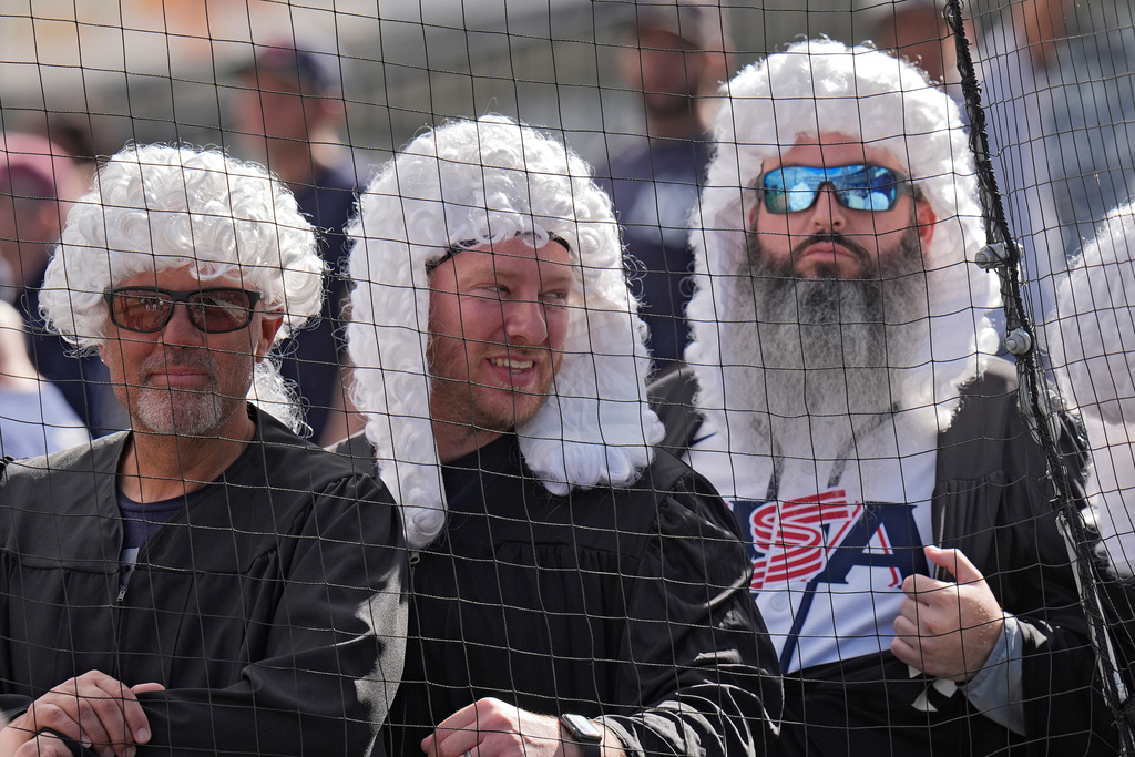 New York Yankees fans, wearing powdered judge's wigs, watch Aaron Judge take batting practice during a spring training baseball workout Monday, Feb. 16, 2026, in Tampa, Fla. (AP Photo/Chris O'Meara)