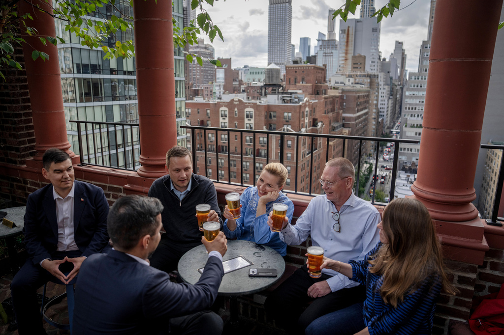 Denmark's Prime Minister Mette Frederiksen, center, Greenland's leader Jens-Frederik Nielsen, second left, and Greenland's Minister for Foreign Affairs Múte B. Egede, foreground left, have a beer with delegation members at a bar in Manhattan, New York after an agreement with the US was signed, Tuesday, Sept. 22, 2026. (Mads Claus Rasmussen/Ritzau Scanpix via AP)