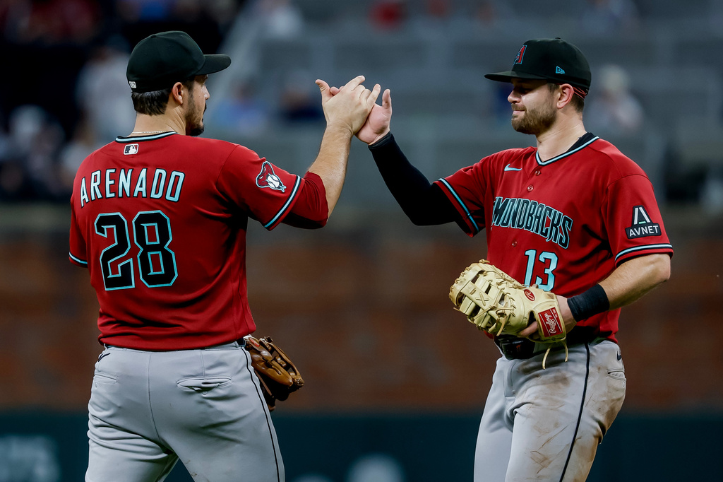 Arizona Diamondbacks third baseman Nolan Arenado (28) celebrates with first baseman Tim Tawa (13) after the Diamondbacks defeated the Atlanta Braves during the ninth inning of a baseball game, Saturday, August 15, 2026, in Atlanta. (AP Photo/Erik S. Lesser)