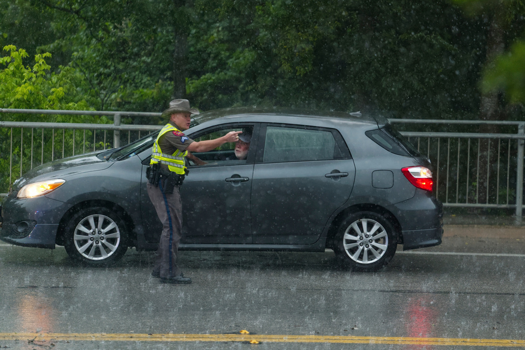 A Texas State Trooper speaks with a motorist who had attempted to drive through flood waters on Wednesday, July 15, 2026, in Boerne, Texas. (AP Photo/Darren Abate)
