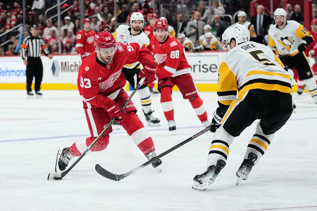 Detroit Red Wings right wing Alex Debrincat, left, moves the puck against Pittsburgh Penguins defenseman Ryan Shea during the second period of an NHL hockey game Saturday, Jan. 3, 2026, in Detroit. (AP Photo/Ryan Sun)