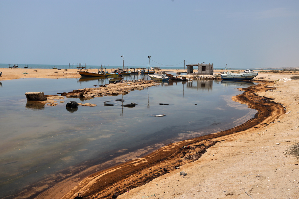 Oil residue lines the shore near fishing boats on Qeshm Island, Iran, Thursday, Aug. 13, 2026, amid ongoing wartime attacks on vessels and infrastructure in and around the Strait of Hormuz, though the spill's source has not been independently determined.(Amirhosein Khorgooi/ISNA via AP)