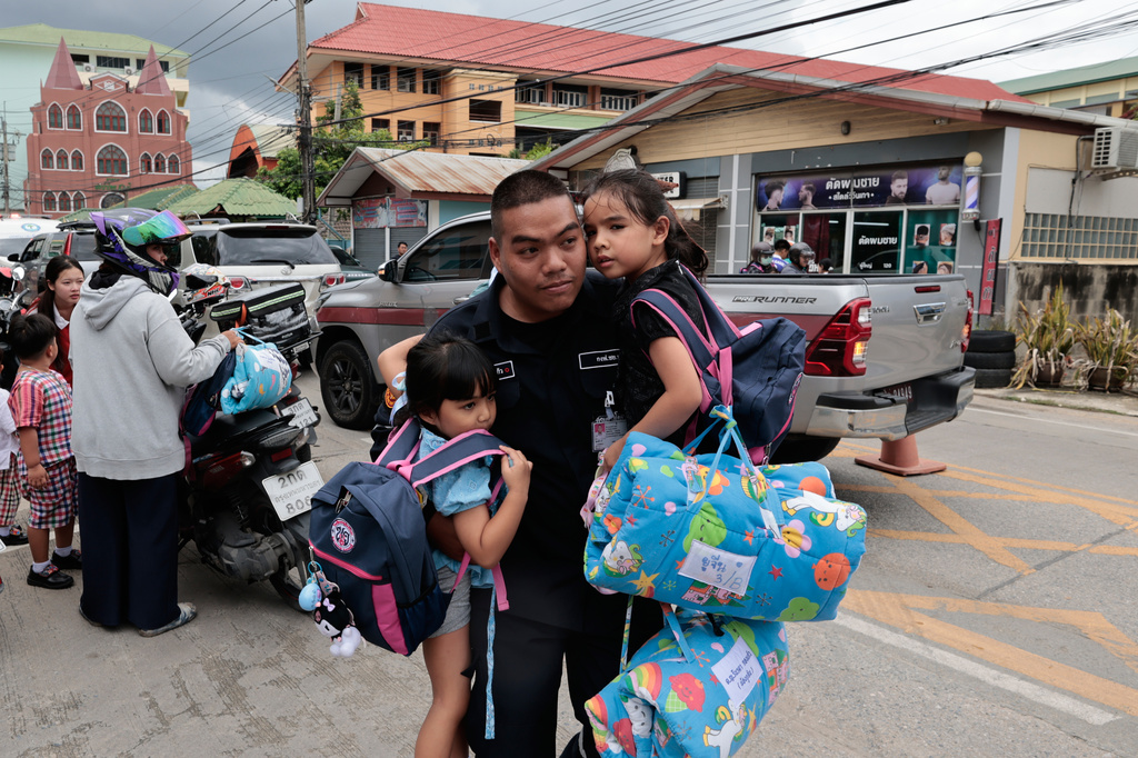 A man carries schoolgirls outside the site of a school shooting in Thailand's Nonthaburi province, Friday, Aug. 7, 2026. (AP Photo/Wason Wanichakorn)