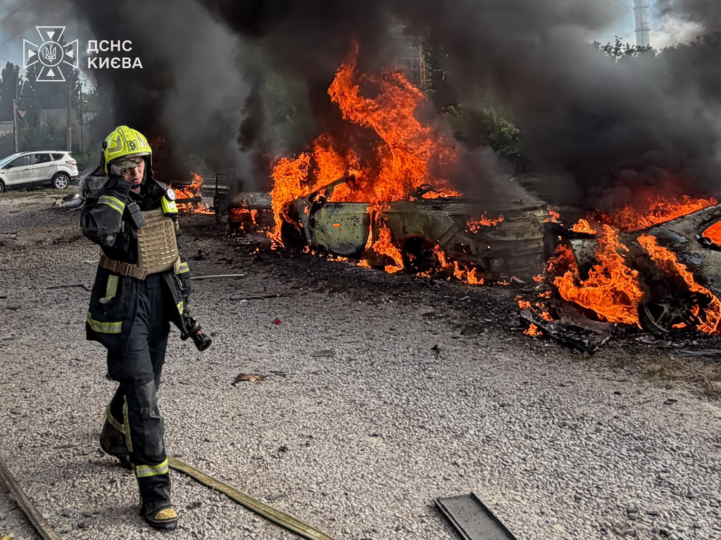 In this photo provided by the Ukrainian Emergency Service, a firefighters walk past burning cars as they work at the site, following a Russian air attack in Kyiv, Ukraine, Wednesday, Sept. 16, 2026. (Ukrainian Emergency Service via AP)