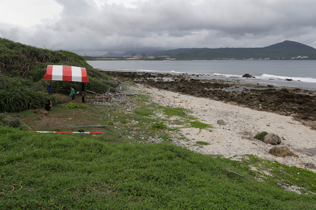 Local volunteers set up a tent before their excavation work to find remains of Japanese soldiers who died during WWII and washed ashore on the coastline of Hengchun township, Pingtung county, southern Taiwan, Sunday, July 19, 2026. (AP Photo/Chiang Ying-ying)
