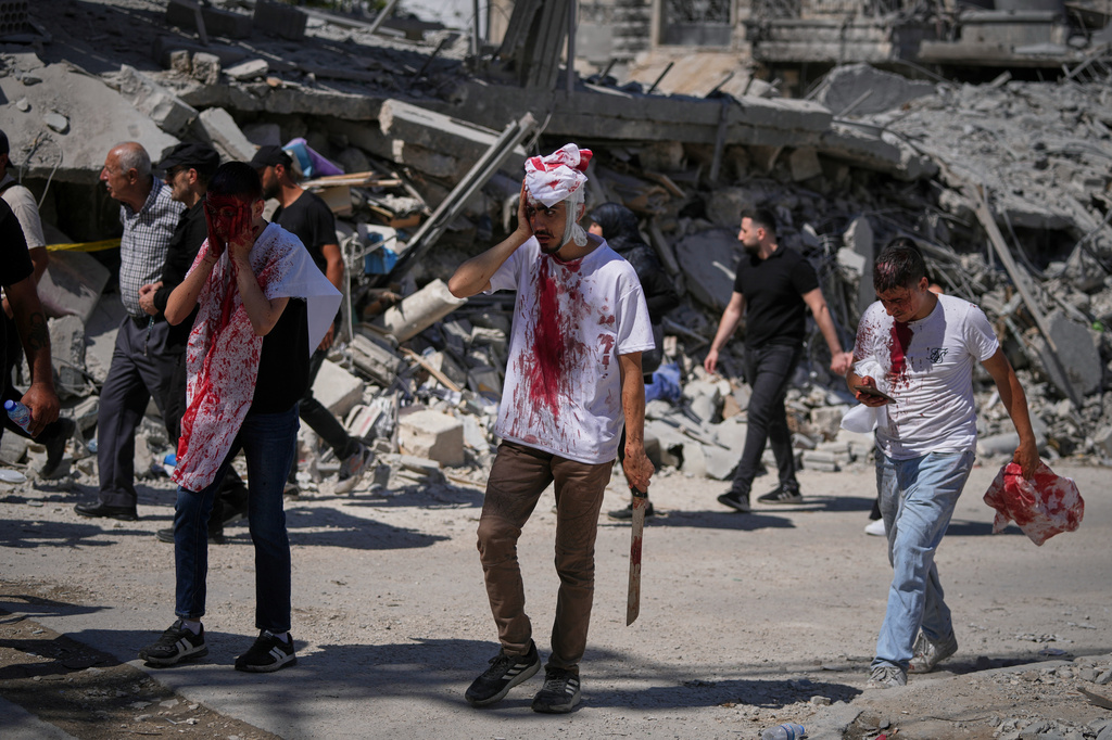 EDS NOTE: GRAPHIC CONTENT - Bleeding from self-inflicted ceremonial head wounds, Lebanese Shiite men walk past buildings destroyed by Israeli strikes during Ashoura, when Shiites commemorate the martyrdom of Imam Hussein, the grandson of the Prophet Muhammad, in Nabatiyeh, southern Lebanon, Friday, June 26, 2026. (AP Photo/Hassan Ammar)