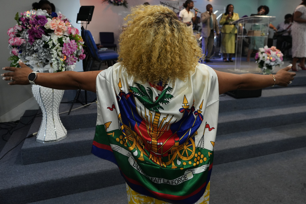 Marjorie Estimé prays wearing a Haitian flag during a service at the Word of Life Center church in Salisbury, Md., Sunday, Aug. 2, 2026. (AP Photo/Luis Andres Henao)