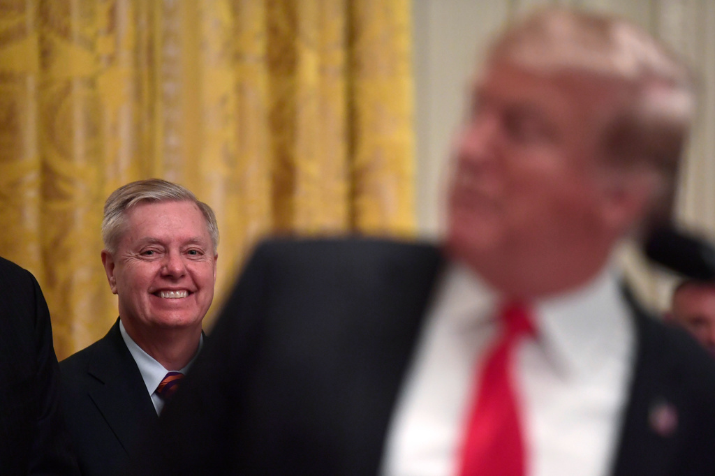 FILE - Sen. Lindsey Graham, R-S.C., left, listens as President Donald Trump speaks during a reception for the Clemson Tigers in the East Room of the White House in Washington, Jan. 14, 2019. (AP Photo/Susan Walsh, File)