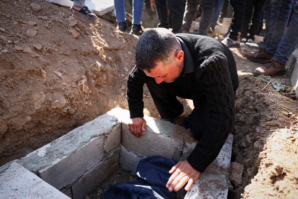 A man weeps over the grave of one of three people killed when gunmen on motorcycles fired on a van near the Druze village of Kafr Maris in Syria's Idlib province, Wednesday, Oct. 22, 2025. (AP Photo/Omar Albam)