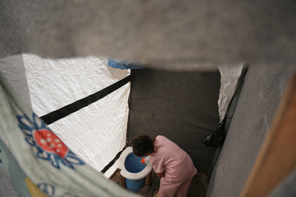 Sila Darwish pours water into a makeshift toilet at her family's tent in Khan Younis, southern Gaza Strip, Wednesday, June 3, 2026. (AP Photo/Abdel Kareem Hana)