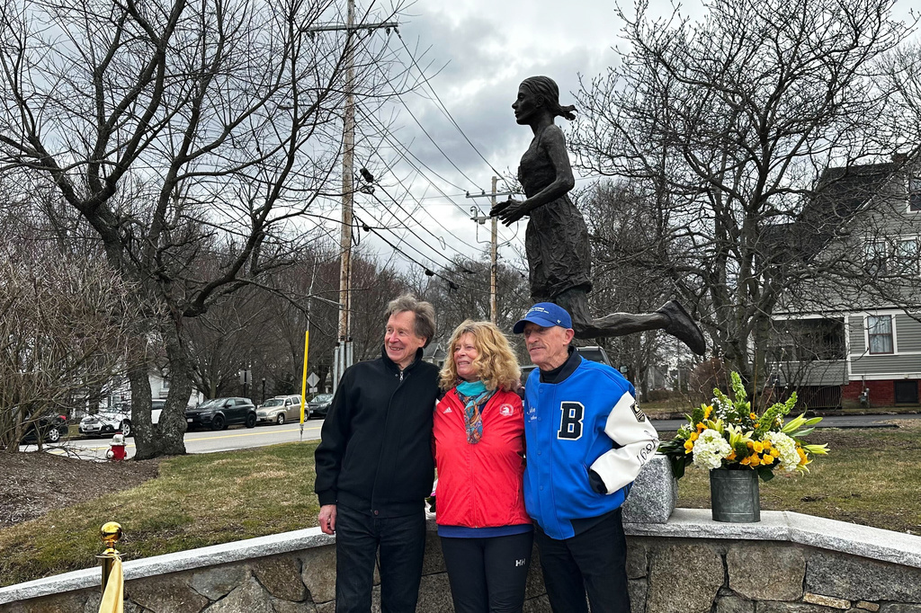 From left, Bill Rodgers, Bobbi Gibb and Jack Fultz pose for a photo in front of her bronze self-portrait during a ribbon cutting ceremony March 27, 2026, in Hopkinton, Mass. (AP Photo/Jimmy Golen)