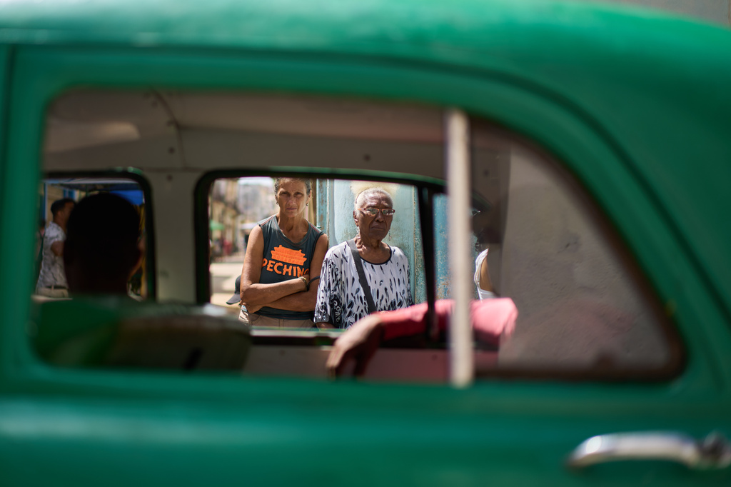 Seen through the window of a passing American classic car, seniors stand in line to buy bread in Old Havana, Cuba, Friday, April 10, 2026. (AP Photo/Ramon Espinosa)