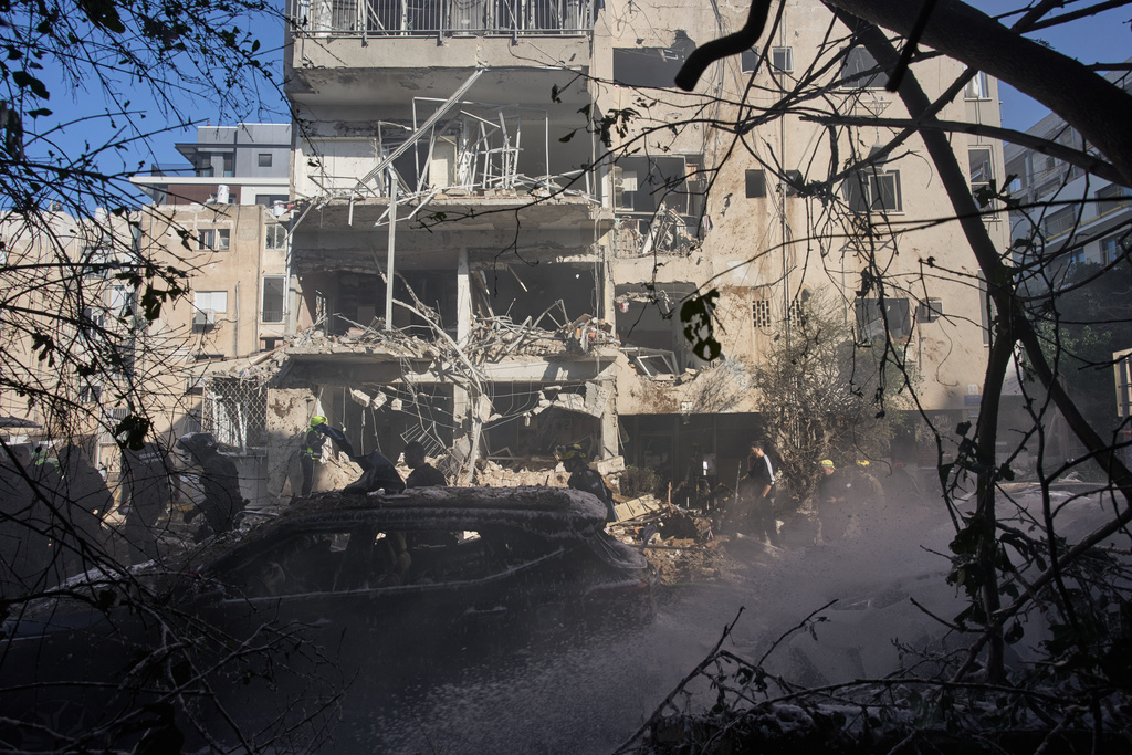 Israeli security forces and rescue team respond at the site of an Iranian missile strike in Tel Aviv, Israel, Tuesday, March 24, 2026. (AP Photo/Oded Balilty)