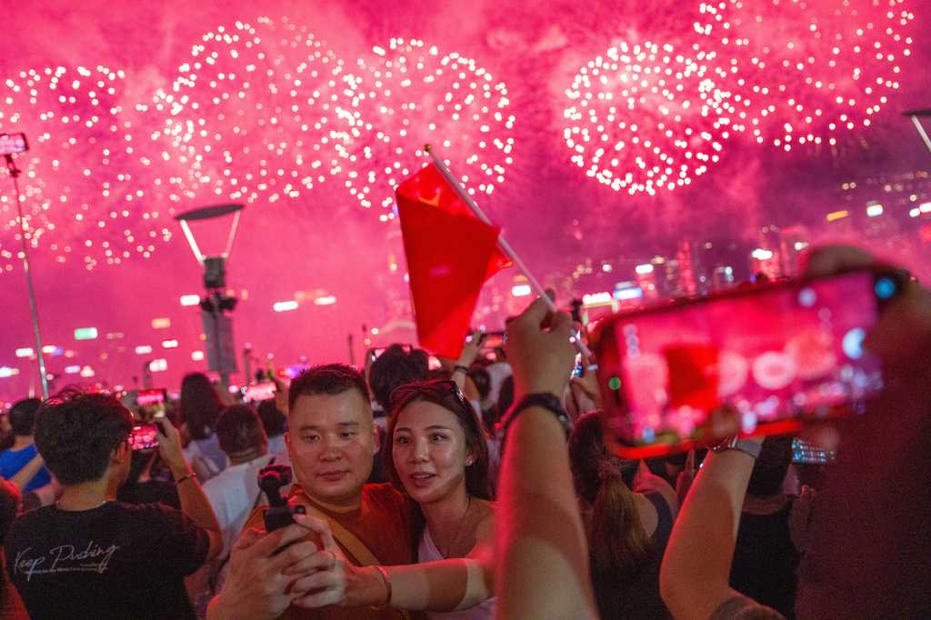 People take a selfie as fireworks explode over Victoria Harbor to mark the National Day of the People's Republic of China in Hong Kong, Thursday, Oct. 1, 2026. (AP Photo/Vernon Yuen)