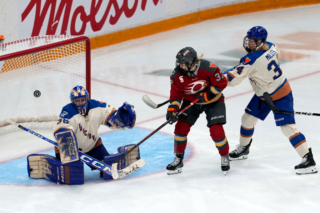 Ottawa Charge's Rebecca Leslie (37) and Vancouver Goldeneyes' Hannah Miller (34) watch the puck as it bounces in front of goaltender Emerance Maschmeyer (38) during the third period of a PWHL hockey game, in Ottawa, Ontario, Wednesday, Nov. 26, 2025. (Justin Tang/The Canadian Press via AP)