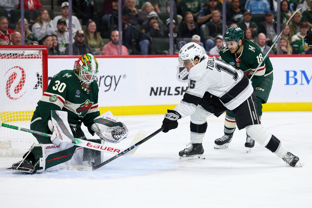Minnesota Wild goaltender Jesper Wallstedt, left, makes a save against a shot by Los Angeles Kings center Alex Turcotte, front left, during the second period of an NHL hockey game Monday, Oct. 13, 2025, in St. Paul, Minn. (AP Photo/Matt Krohn)