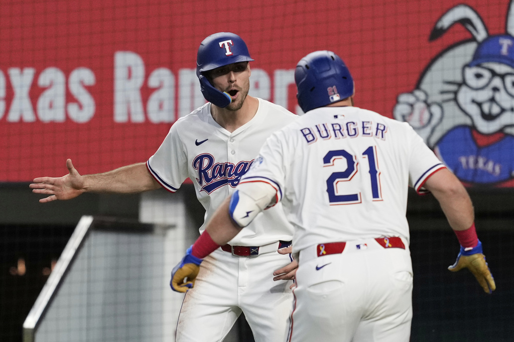 Texas Rangers' Evan Carter, left, and Jake Burger (21) celebrate Burger's two run home run that scored Carter in the fourth inning of a baseball game against the Arizona Diamondbacks Wednesday, Aug. 13, 2025, in Arlington, Texas. (AP Photo/Tony Gutierrez)