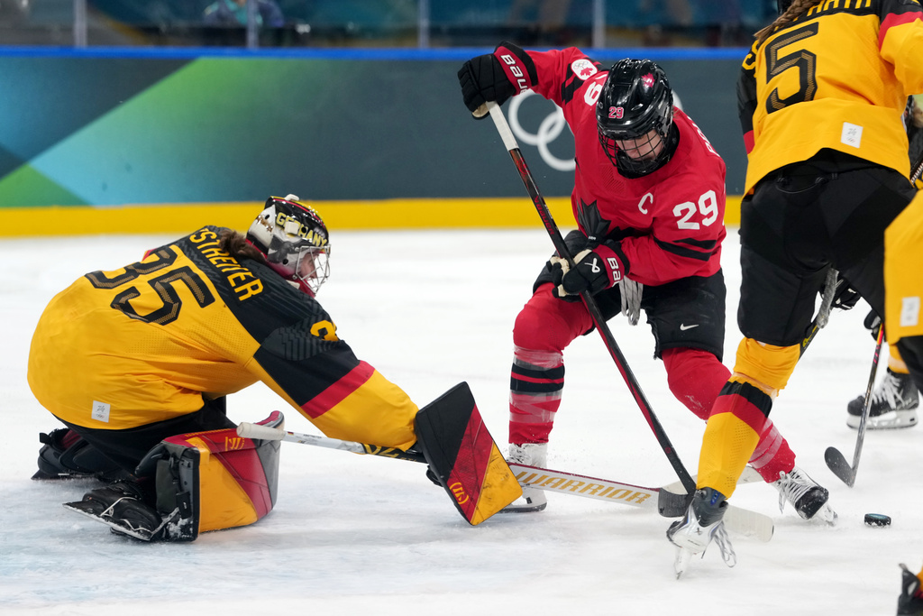 Canada's Marie-Philip Poulin (29) tries to control the puck in front of Germany goalkeeper Sandra Abstreiter (35) during the second period of a women's ice hockey quarterfinal match at the 2026 Winter Olympics, in Milan, Italy, Saturday, Feb. 14, 2026. (AP Photo/Carolyn Kaster)