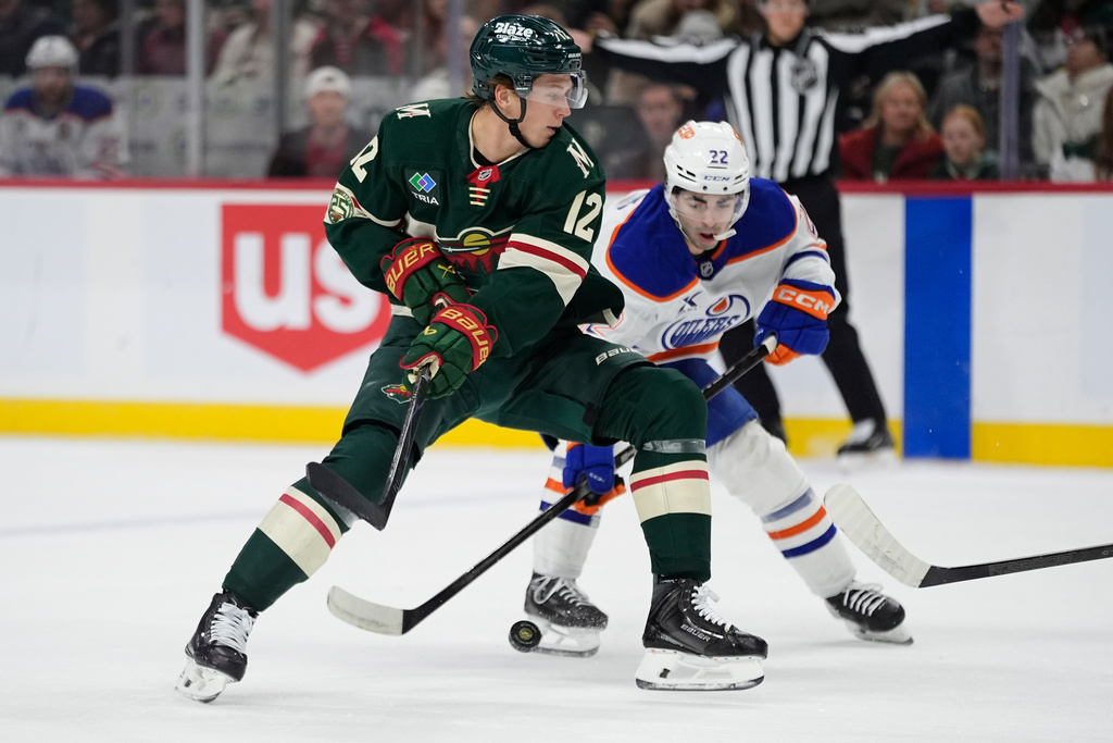 Minnesota Wild left wing Matt Boldy (12) and Edmonton Oilers center Matt Savoie (22) battle for the puck during the first period of an NHL hockey game, Saturday, Dec. 20, 2025, in St. Paul, Minn. (AP Photo/Abbie Parr)