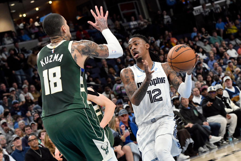 Memphis Grizzlies guard Ja Morant (12) drives against Milwaukee Bucks forward Kyle Kuzma (18) in the first half of an NBA basketball game Friday, Dec. 26, 2025, in Memphis, Tenn. (AP Photo/Brandon Dill)