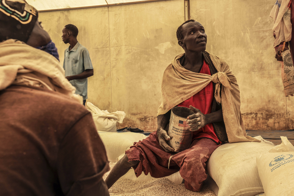 A man scoops up portions of wheat to be allocated to each waiting family after distribution by the U.N. World Food Programme (WFP) in the Gendrassa Refugee Camp, Maban, South Sudan, Wednesday, Aug. 20, 2025. (AP Photo/Caitlin Kelly)