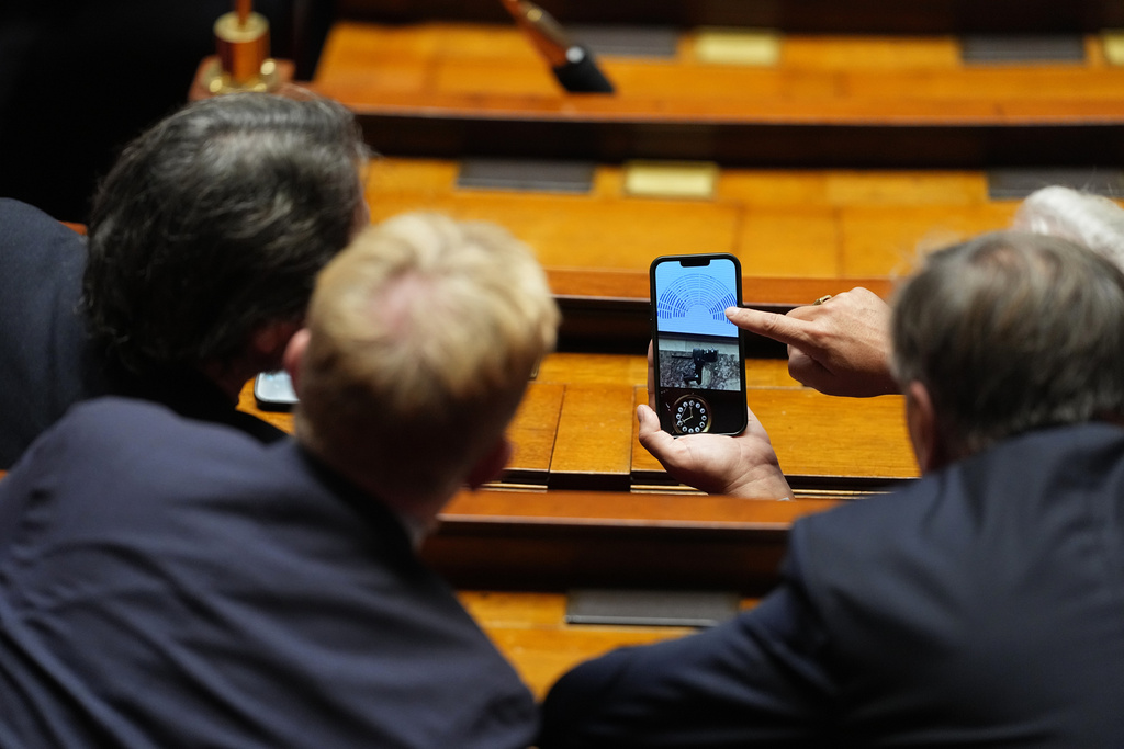 Lawmakers look on a phone at the National Assembly the results of a no-confidence motion vote on French Prime Minister Sébastien Lecornu's government in Paris, Thursday, Oct. 16, 2025. (AP Photo/Thibault Camus)