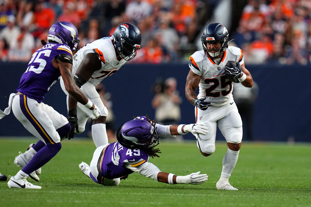 Denver Broncos running back Cody Schrader (25) runs from Minnesota Vikings outside linebacker Cam'Ron Stewart (49) during the first half of a preseason NFL football game, Friday, Aug. 28, 2026, in Denver. (AP Photo/Jack Dempsey)