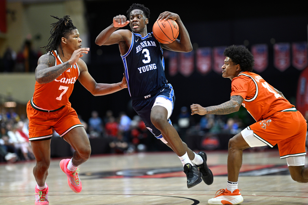 BYU forward AJ Dybantsa (3) drives to the basket between Miami forward Shelton Henderson (7) and guard Tru Washington, right, during the second half of an NCAA college basketball game, Thursday, Nov. 27, 2025, in Kissimmee, Fla. (AP Photo/Phelan M. Ebenhack)