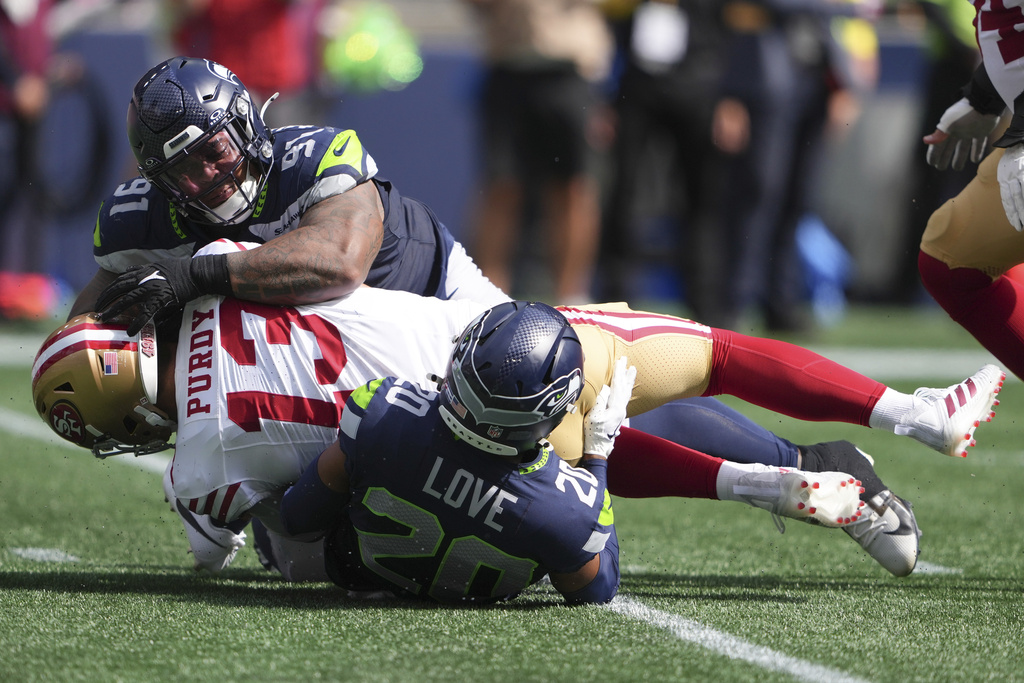 Seattle Seahawks safety Julian Love (20) and defensive tackle Byron Murphy II (91) bring down San Francisco 49ers quarterback Brock Purdy during the first half of an NFL football game Sunday, Sept. 7, 2025, in Seattle. (AP Photo/Lindsey Wasson)