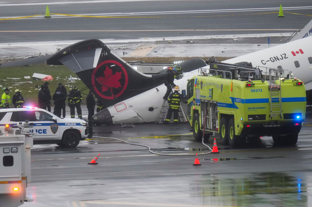 FILE - Firefighters and investigators examine the site, Monday, March 23, 2026, where an Air Canada jet came to rest after colliding with a Port Authority firetruck at LaGuardia Airport, after landing Sunday night in New York. (AP Photo/Seth Wenig, File)