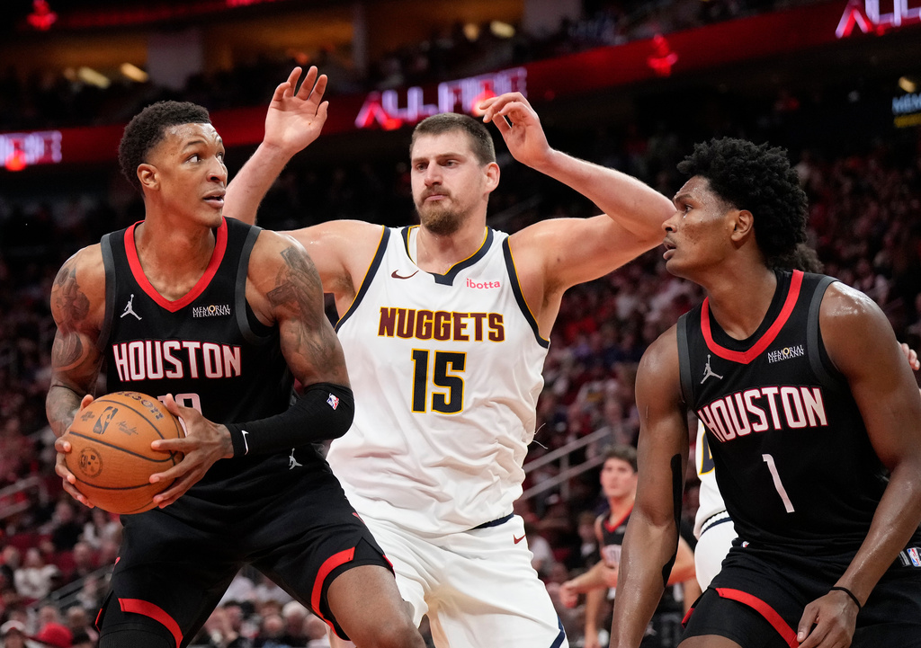 Houston Rockets forward Jabari Smith Jr. (10) looks to shoot a basket against Denver Nuggets center Nikola Jokic (15) and Rockets guard Amen Thompson (1) during the second half of an NBA Cup basketball game, Friday, Nov. 21, 2025, in Houston. (AP Photo/Karen Warren)