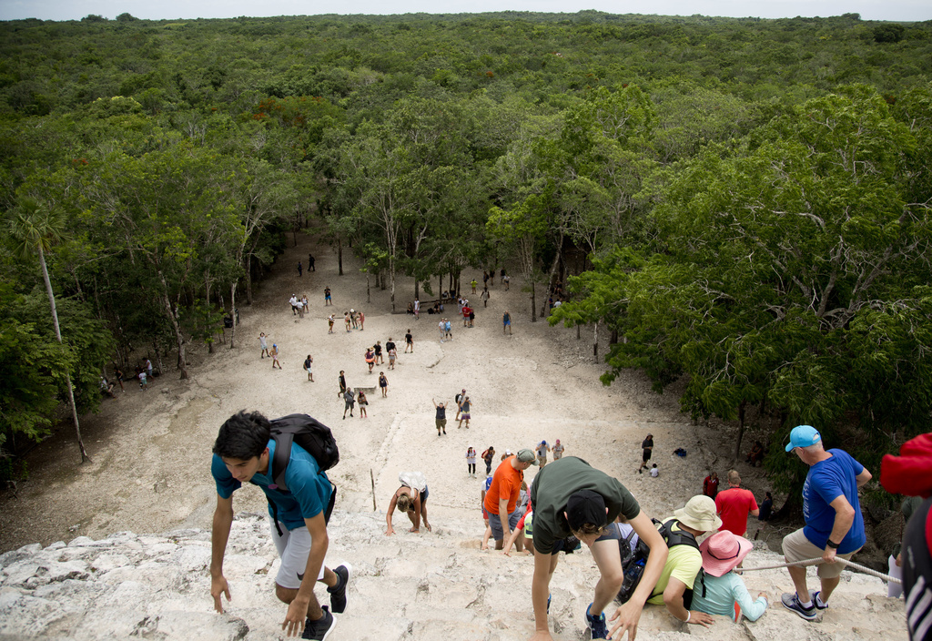 FILE - Tourists climb a Mayan temple at the archeological site of Coba, in Mexico's Yucatan Peninsula, Aug. 1, 2018. (AP Photo/Eduardo Verdugo, File)