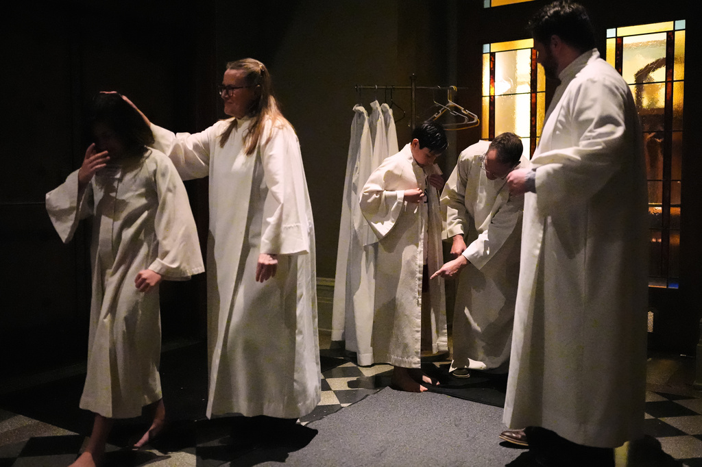 Neophytes get dressed in their new white robes after being baptized at an Easter vigil at St. James Cathedral, Saturday, April 4, 2026, in Seattle. (AP Photo/Lindsey Wasson)