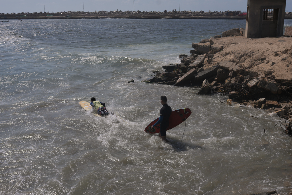Palestinians Khalil Abu Jayyab, left, and Abed Rahim Alostaz enter the waters of the Mediterranean Sea to surf at the beach in Gaza City, Monday, May 4, 2026. (AP Photo/Jehad Alshrafi)