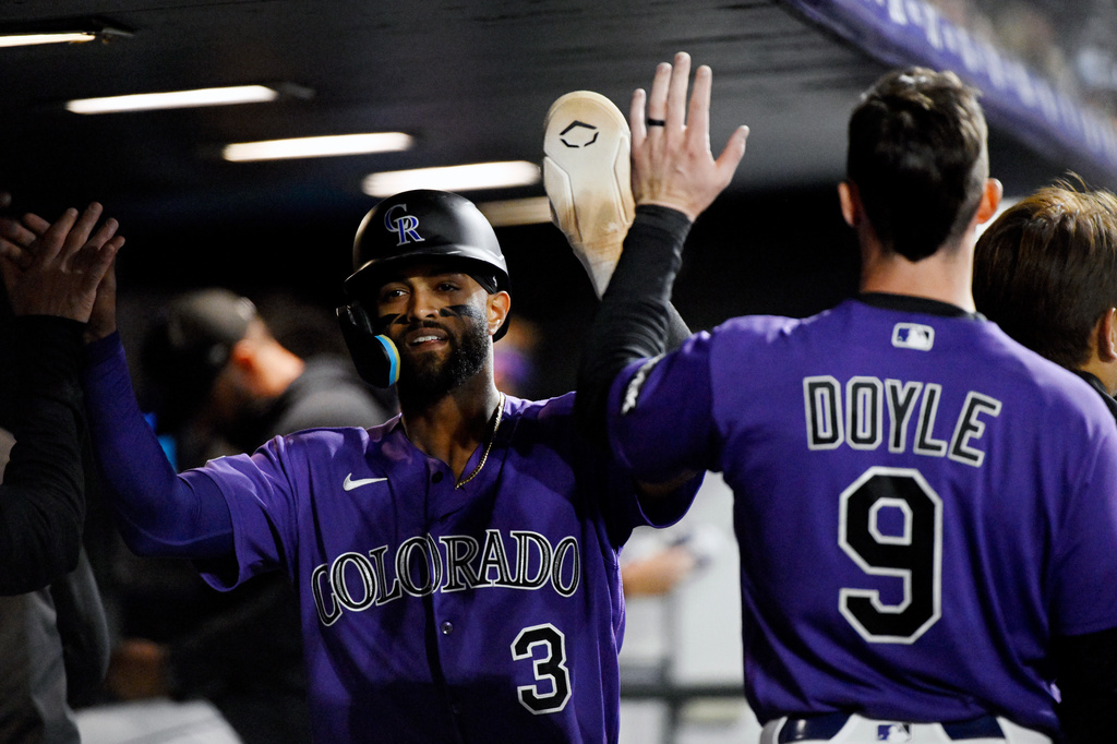 Colorado Rockies' Willi Castro (3) and Brenton Doyle (9) high-five in the dugout after scoring on a two-run single by teammate Edouard Julien in the fifth inning of a baseball game against the Houston Astros, Monday, April 6, 2026, in Denver. (AP Photo/Geneva Heffernan)