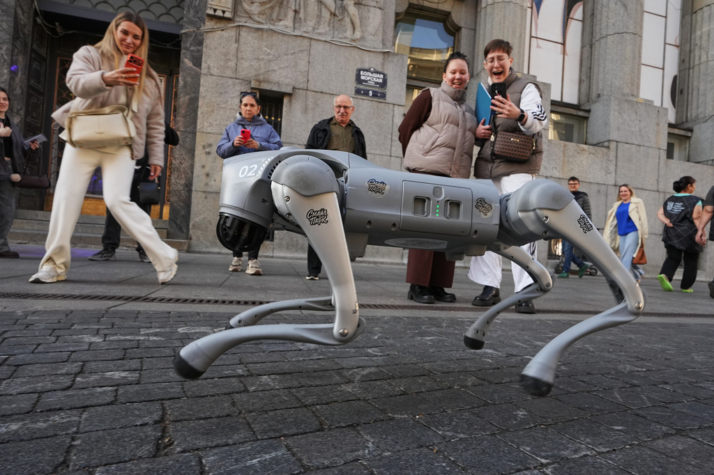 People look at an animal shaped robot promoting a nearby entertainment museum in St. Petersburg, Russia, Thursday, Oct. 1, 2026. (AP Photo/Dmitri Lovetsky)