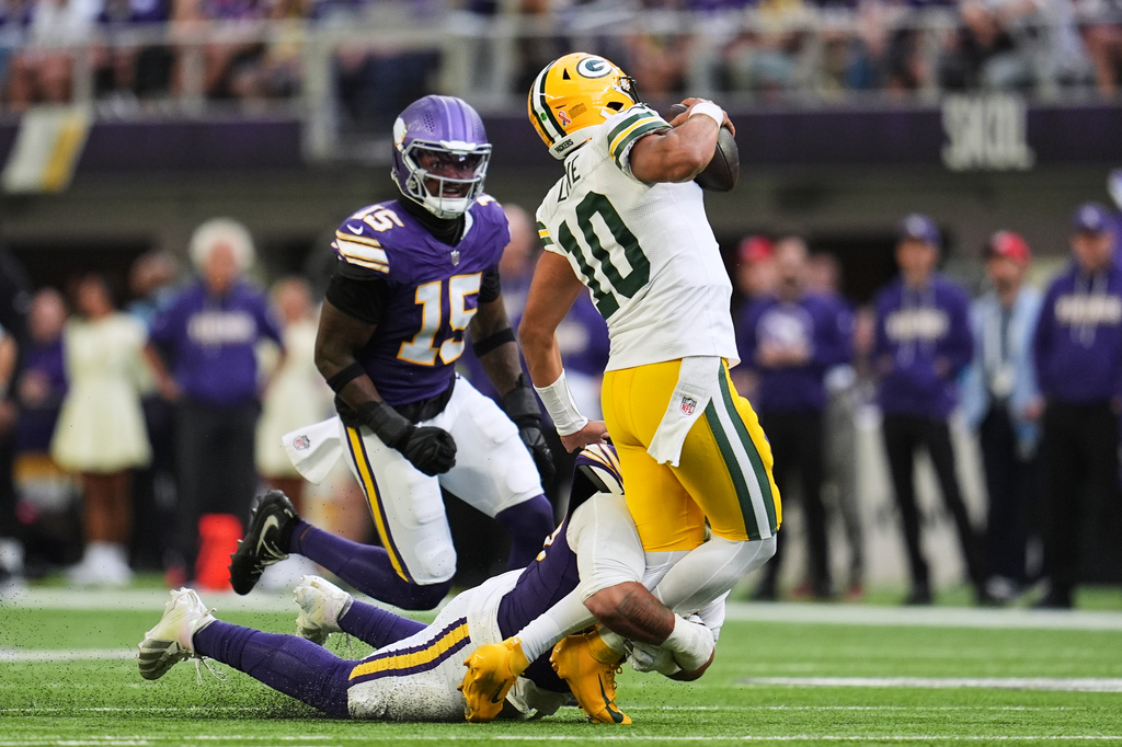 Green Bay Packers quarterback Jordan Love (10) is sacked by Minnesota Vikings defensive tackle Levi Drake Rodriguez, bottom, as Dallas Turner (15) looks on during the second half of an NFL football game, Sunday, Sept. 13, 2026, in Minneapolis, Minn. (AP Photo/Abbie Parr)