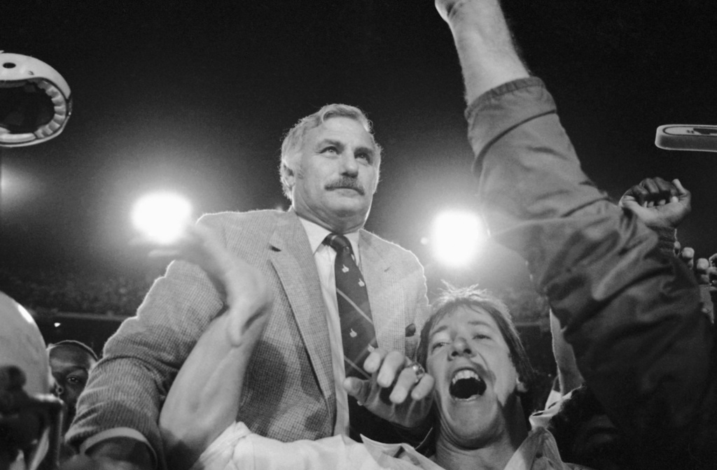 FILE -University of Miami's coach Howard Schnellenberger is carried from the field by jubilant Miami Hurricane players after they upset the Cornhuskers of Nebraska at Miami's Orange Bowl 31-30, Jan. 2, 1984. (AP Photo/Doug Jennings, File)