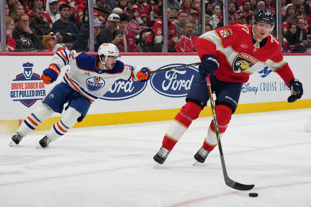 Florida Panthers defenseman Niko Mikkola (77) skates past Edmonton Oilers center Matt Savoie, left, during the first period of an NHL hockey game, Saturday, Nov. 22, 2025, in Sunrise, Fla. (AP Photo/Lynne Sladky)